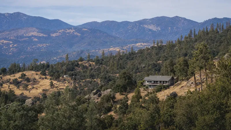 Fresno County, California: Oak-to-pine foothill transition with granite boulders; house on a dry slope; high ridges far off