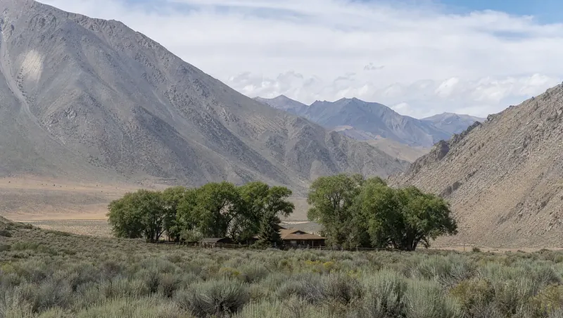 Inyo County, California: Arid sagebrush valley under steep barren mountains; ranch home with cottonwoods