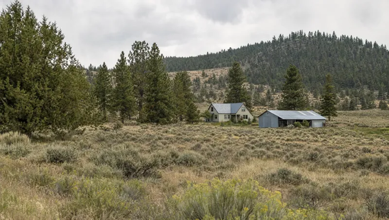 Lassen County, California: Sagebrush and juniper plateau meeting pine forest; ranch house with metal barn
