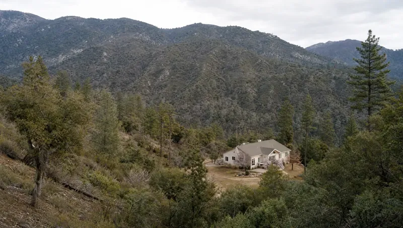 Madera County, California: Gray pine, oak and manzanita foothills; home with cleared ground; forested mountains behind