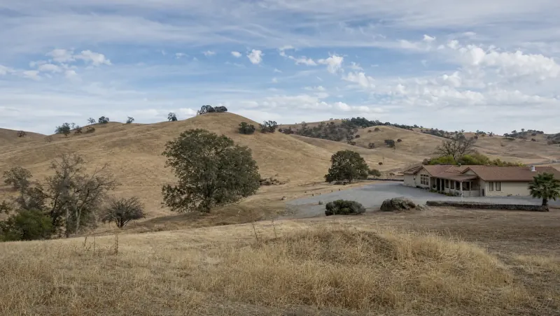 Merced County, California: Dry rolling grassland with sparse oaks; ranch home with gravel yard