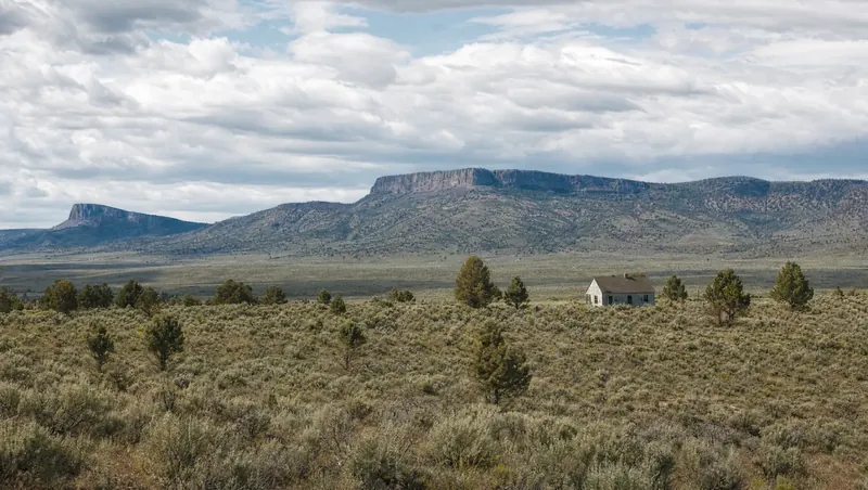 Modoc County, California: Huge sagebrush/juniper high desert with dark volcanic rimrock; lone ranch house; big sky