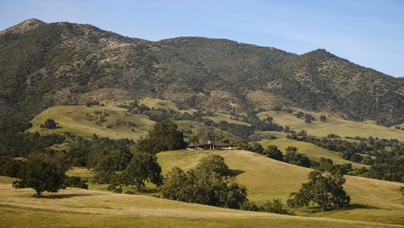 San Luis Obispo County, California: Rolling green-gold hills with live oaks; ranch house on a knoll; chaparral on higher ridges
