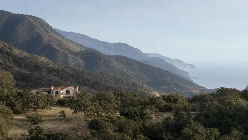 Santa Barbara County, California: Steep chaparral foothills behind an oak-dotted coastal plain; Mediterranean home among oaks; ocean haze