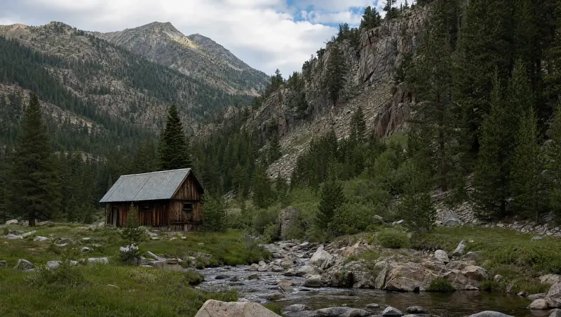Sierra County, California: Conifer-filled mountain canyon, rocky ridges; small cabin with metal roof near a creek