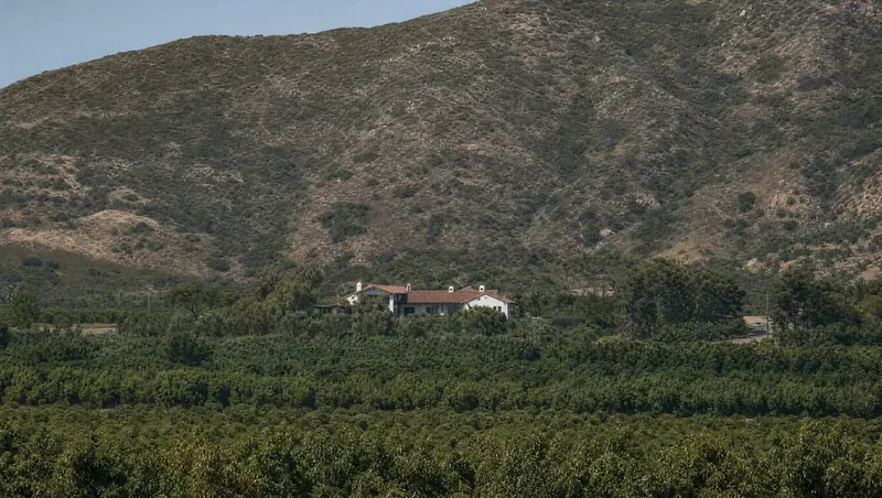 Ventura County, California: Sage-scrub hills over avocado/citrus orchards; Spanish-style ranch house at the foot of the hills